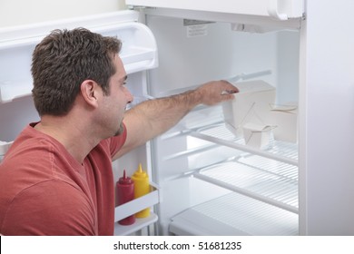 Attractive Caucasian Male Reaching Into A Sparse Refrigerator