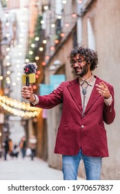 attractive caucasian man recording himself in the streets of Barcelona. He is holding a gimbal with a yellow mobile phone and a microphone. He is dressing casual with blue jeans and red jacket.
