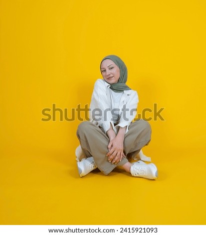 Attractive caucasian Muslim girl wear hijab sit floor lotus pose legs crossed smiling to camera. Full body view young amazing beautiful islam religious woman. Cute 20s girl lifestyle concept. 