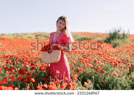 Attractive caucasian woman at a blooming poppy field. Beauty woman in red dress and straw handbag with wild flowers