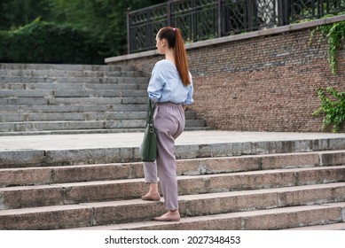 Attractive Caucasian young woman in formal wear walks up the steps in the city on a warm summer day. Back view. Progress and success of a businesswoman. - Powered by Shutterstock