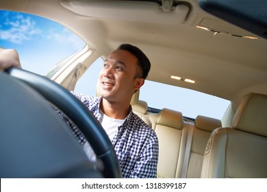 Attractive And Charming Asian Man Driving A Car In Confident Look In  Casual Shirt. Happy Guy Driving A Car