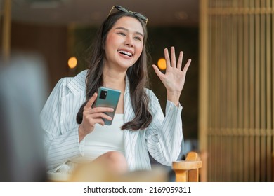 Attractive Cheerful Asian Female Adult Gesture Hand Wave To Say Hi To Her Friend Walking In Cafe Restaurant,asian Woman Hand Hold Coffee Cup Relax Casual Greeting To Her Friend In Cafe 