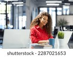 Attractive cheerful business woman in red shirt working on laptop at modern office