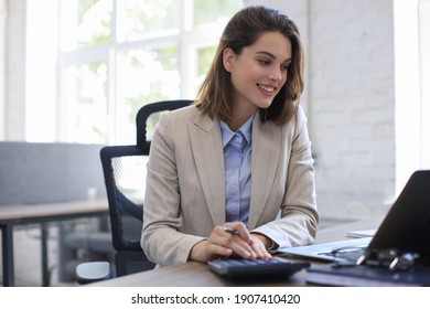 Attractive cheerful business woman working on laptop at modern office - Shutterstock ID 1907410420