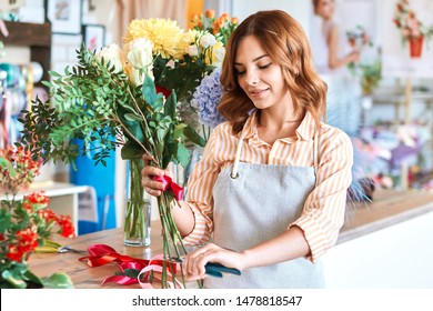 attractive cheerful female florist trimming flower stem in flower shop. close up portrait. job, occupation, profession - Powered by Shutterstock