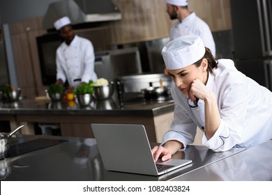 attractive chef using laptop at restaurant kitchen - Powered by Shutterstock