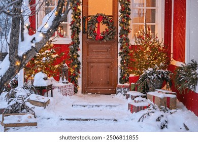 Attractive Christmas entrance decorated with wreath and garlands with snow on the porch. Gift boxes near the door.
