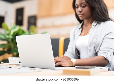 Attractive Concentrated African American Woman Using Laptop In Cafe