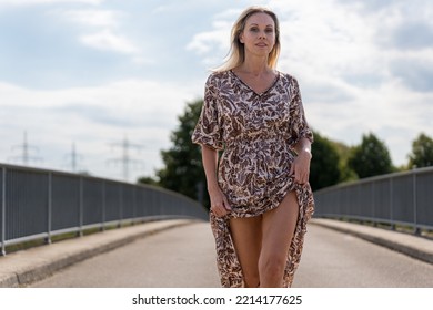 Attractive Confident Provocative Blonde Sexy Middle Aged Woman With A Challenging Look At The Camera On A Bridge