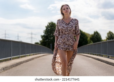 Attractive Confident Provocative Blonde Sexy Middle Aged Woman With A Challenging Look At The Camera On A Bridge