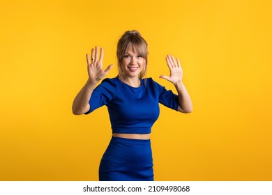 Attractive Confident Woman Raise Palms Calm Down Gesture. Smiling Girl Keeps Palms Outstretched Raises Hands In Stop Motion Looking At Camera On Yellow Background. Relax I Deal It