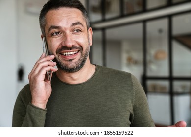 Attractive confident young business man using mobile phone while standing in the office - Shutterstock ID 1855159522