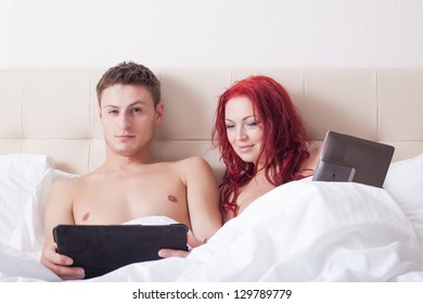 Attractive couple in bed with tablet computers