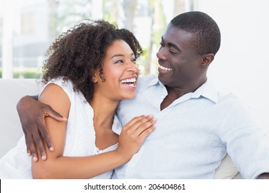 Attractive Couple Cuddling On The Couch At Home In The Living Room