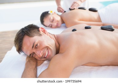 Attractive couple enjoying hot stone massage poolside outside at the spa - Powered by Shutterstock