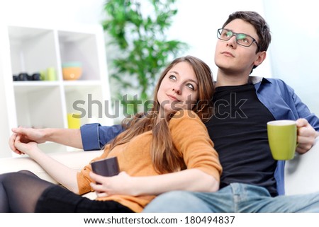 Attractive couple of lovers sitting on a sofa taking a hot drink
