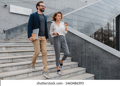 attractive couple of man and woman going on stairs in urban city center in smart casual business style, talking, working together, smiling, stylish freelance people, holding laptop? discussing - Shutterstock ID 1463486393