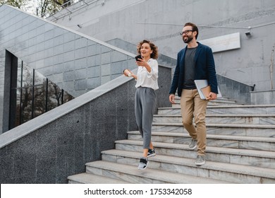 Attractive Couple Of Man And Woman Going On Stairs In Urban City Center In Smart Casual Business Style, Talking, Working Together, Smiling, Stylish Freelance People, Holding Laptop, Discussing