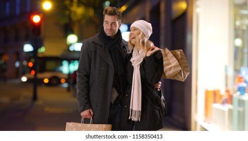 Attractive Couple Shopping In The City At Night Smiling