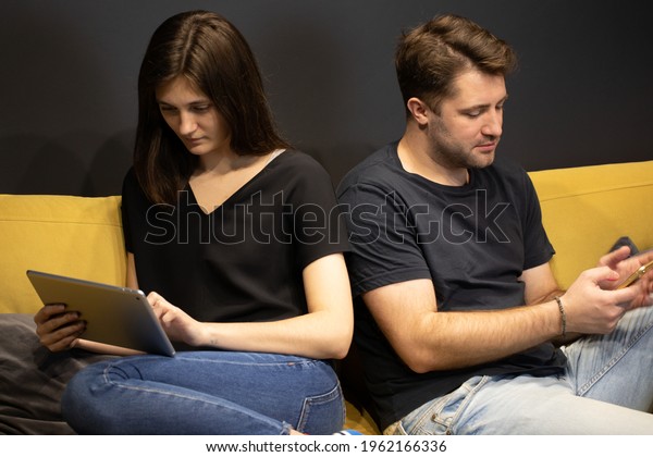 Attractive\
Couple using smartphone and tablet chatting online reading news,\
ignoring presence of boyfriend and girlfriend. Cheating and\
infidelity concept. Jealousy, internet\
lovers