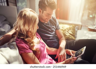 attractive couple using tablet together on futon h at home