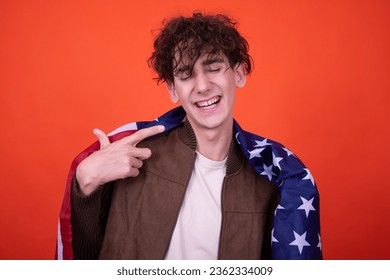 Attractive curly student posing on an orange background with an American flag. - Shutterstock ID 2362334009
