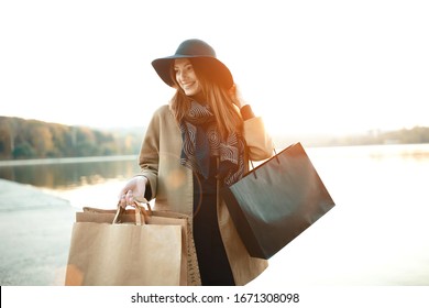 Attraktives süßes Mädchen mit Einkaufstaschen und warmen Getränken in der Hand