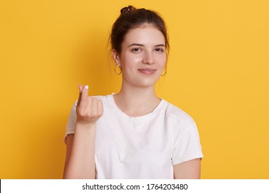 Attractive Dark Haired Woman Shoving Money Gesture With Her Fingers, Looking At Camera With Satisfied Facial Expression, Calls On Her Husband To Give His Salary.