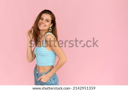 Attractive dark-haired girl in a bright summer outfit smiles with copy space. Positive smiling woman posing on pink background
