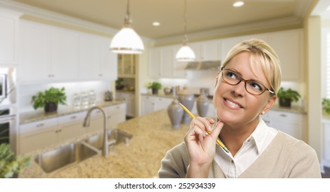 Attractive Daydreaming Woman with Pencil Inside Beautiful Custom Kitchen.