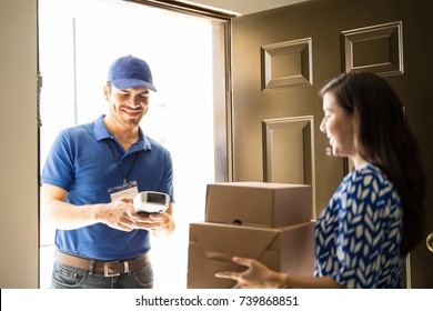 Attractive delivery man handing over some packages to a customer in the front door