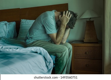 Attractive depressed and upset man at home bedroom . dramatic lifestyle portrait of 30s to 40s handsome guy sitting sad on bed feeling worried and desperate suffering depression problem 
