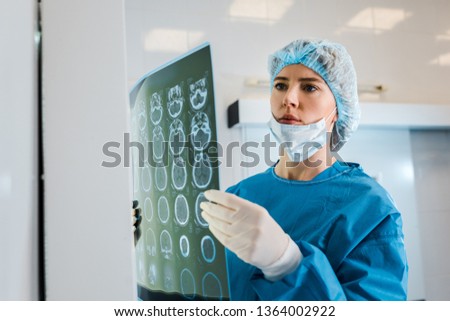 attractive doctor in medical cap and uniform holding x-ray in clinic 