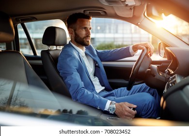 Attractive elegant man in business suit driving car
