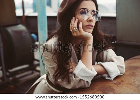 attractive elegant model posing in beige suit and beret on urban roof