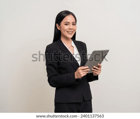Attractive elegant young asian business woman using digital tablet standing on isolated background. Happy young latin female formal black suit holding tablet gadget working service with customer