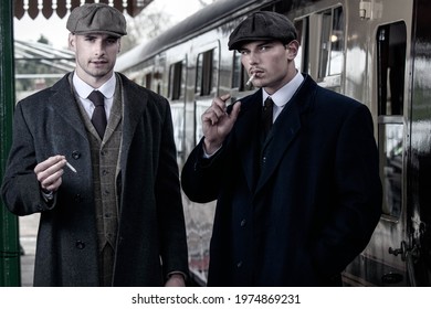 Attractive English gangsters smoking at railway station with train in the background