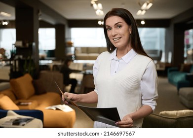 Attractive European Woman, Furniture Store Owner, Successful Sales Rep And Retail Assistant Holding A Catalog With Furniture And Smiles Looking At Camera