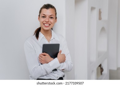 Attractive excited hispanic manager woman in glasses wearing white shirt and black pants holding laptop looking aside dreamily. Beautiful italian young student girl. Mockup, business, financial people
