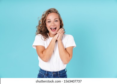 Attractive excited young girl wearing casual clothing standing isolated over blue background, looking at camera