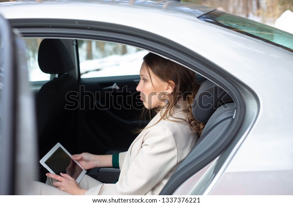 Attractive executive female manager working with a\
tablet in a backseat of a\
car
