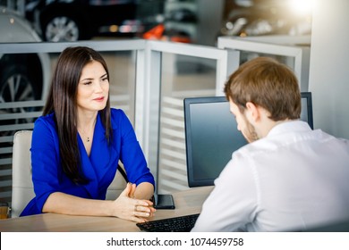 Attractive Fashion Brunette Discussing Price Discounting With Sales Manager While Buying A Car At Car Dealership