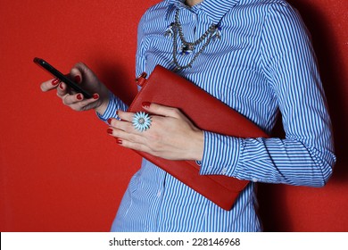Attractive  fashion businesswoman using a smart phone and hold red clutch