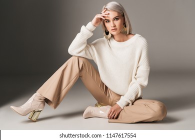 attractive fashionable woman posing in white trendy sweater, beige pants and autumn heels, on grey  - Shutterstock ID 1147617554