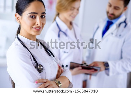 Attractive female arab doctor smiling in front of medical stuff in hospital