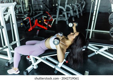 Attractive Female Athlete Doing Dumbell Bench Press In The Gym