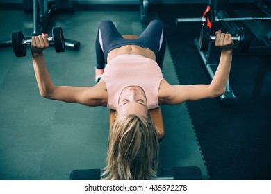 Attractive Female Athlete Doing Dumbell Bench Press In The Gym