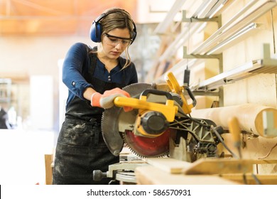 Attractive Female Carpenter Using Some Power Tools For Her Work In A Woodshop