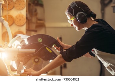 Attractive Female Carpenter Using Some Power Tools For Her Work In A Woodshop